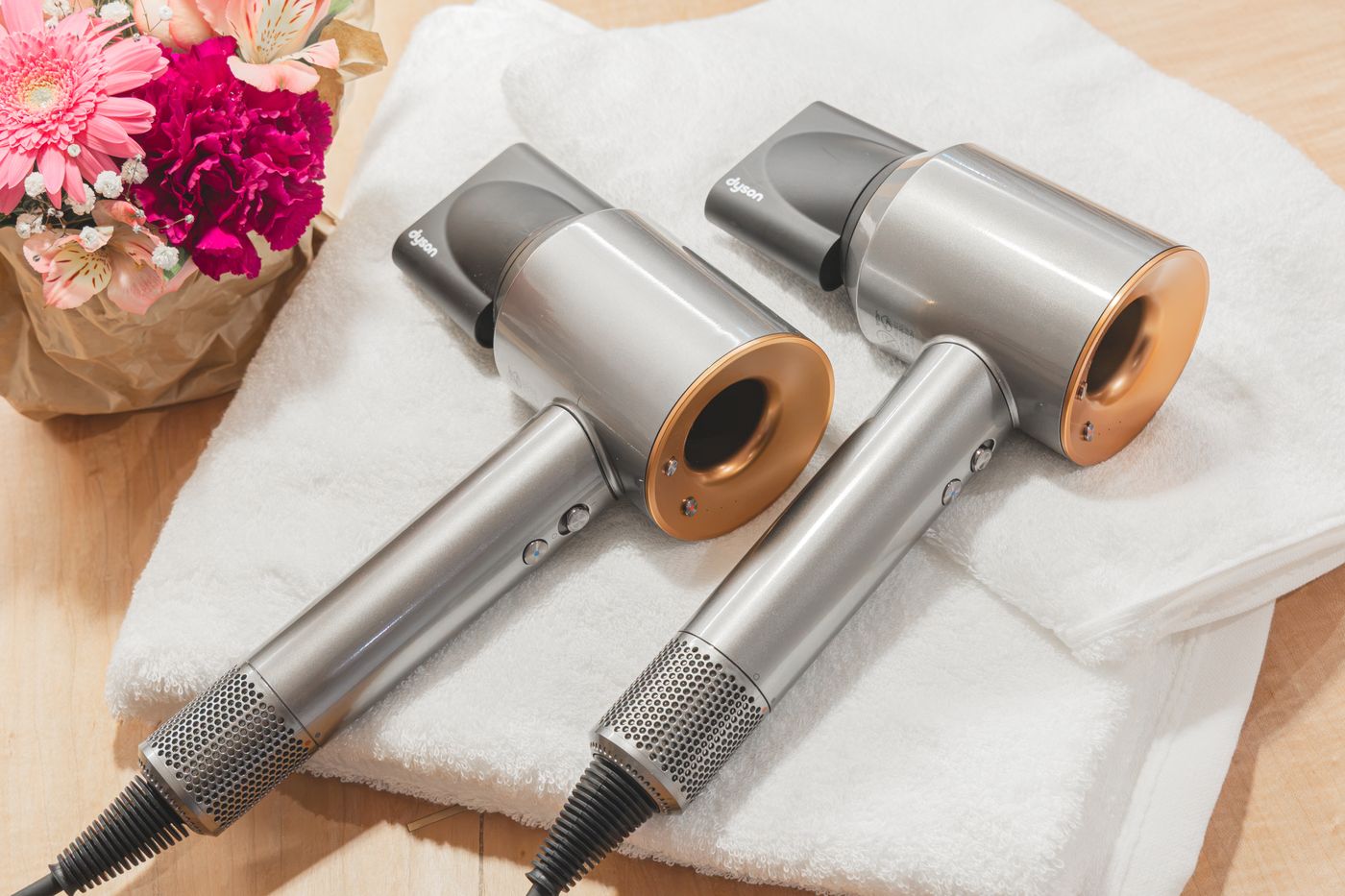 Two hair dryers on folded towels with a bunch of flowers