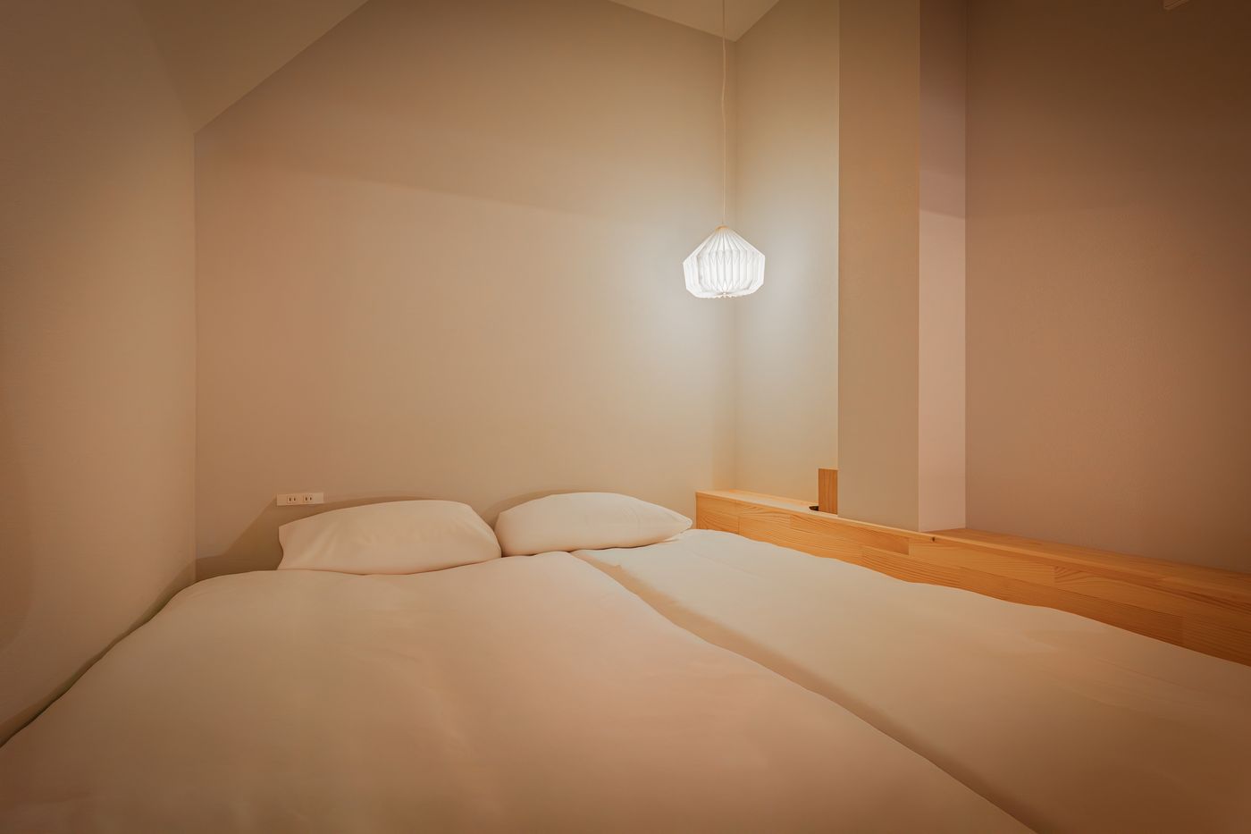 Bedroom two: a bed under a sloped ceiling with a single pendant lamp