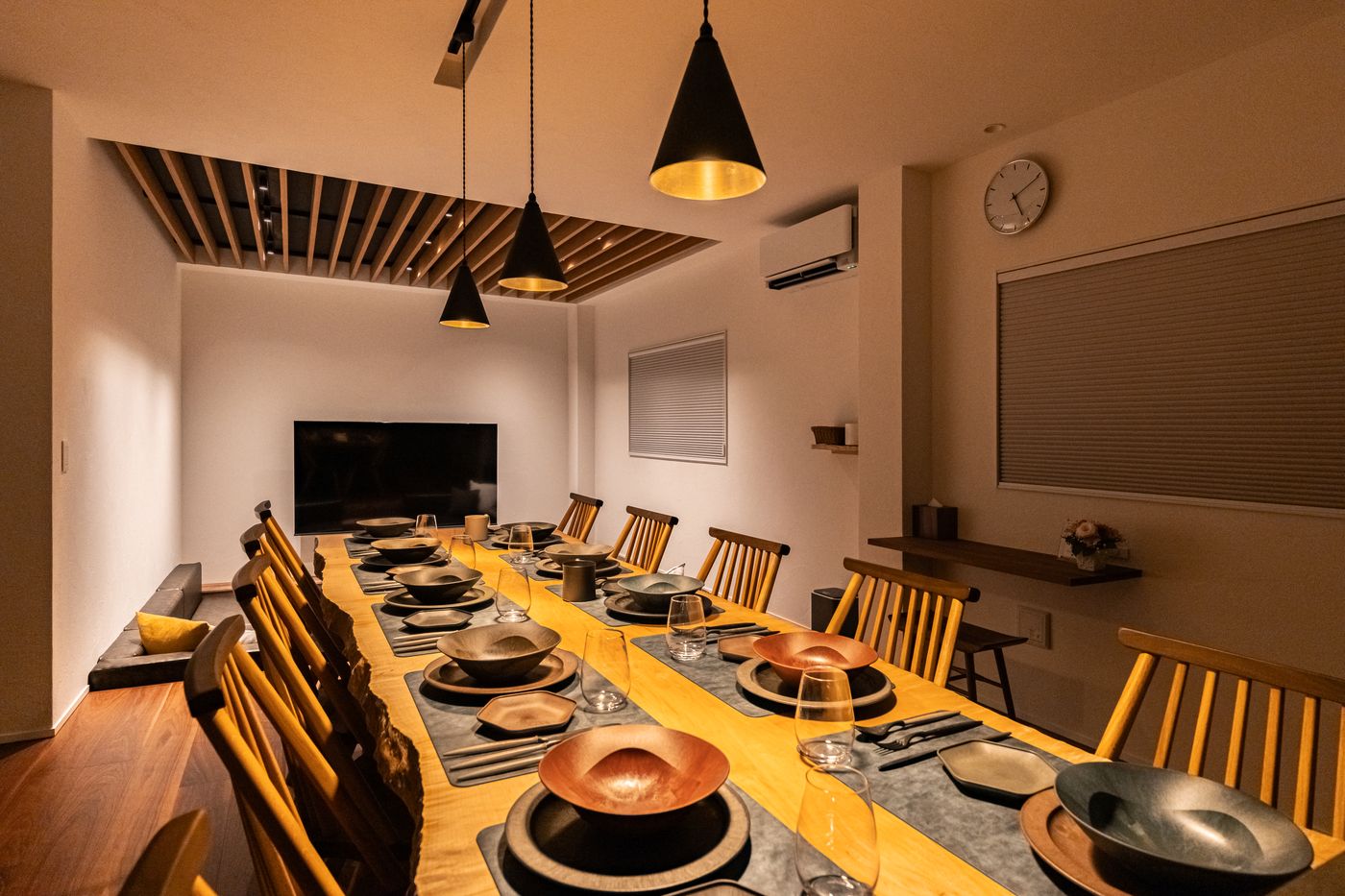 The dining table of Rin seen from the kitchen side, with a wall clock