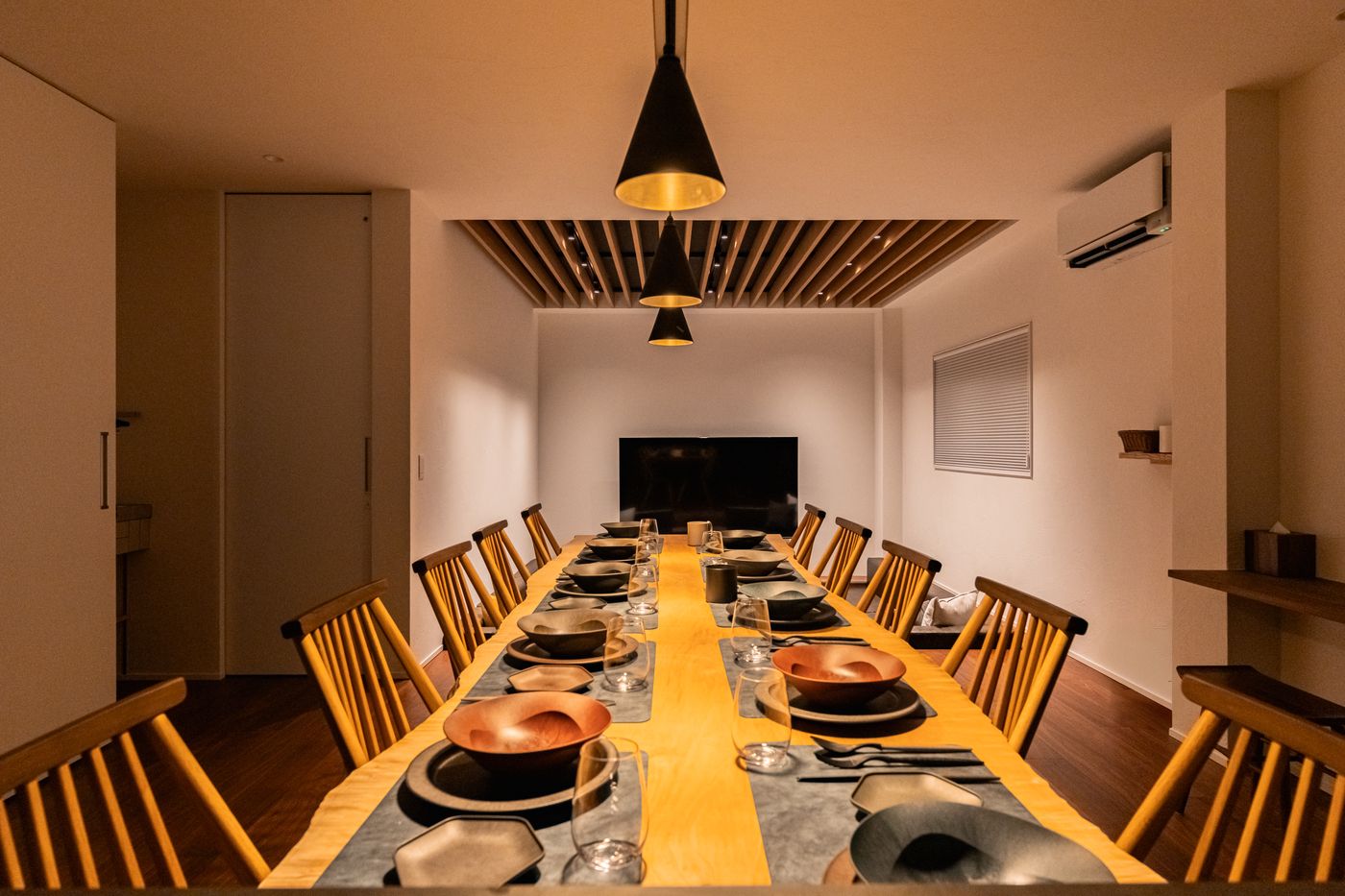 The dining room of Rin: one long table set for a large party under pendant lights