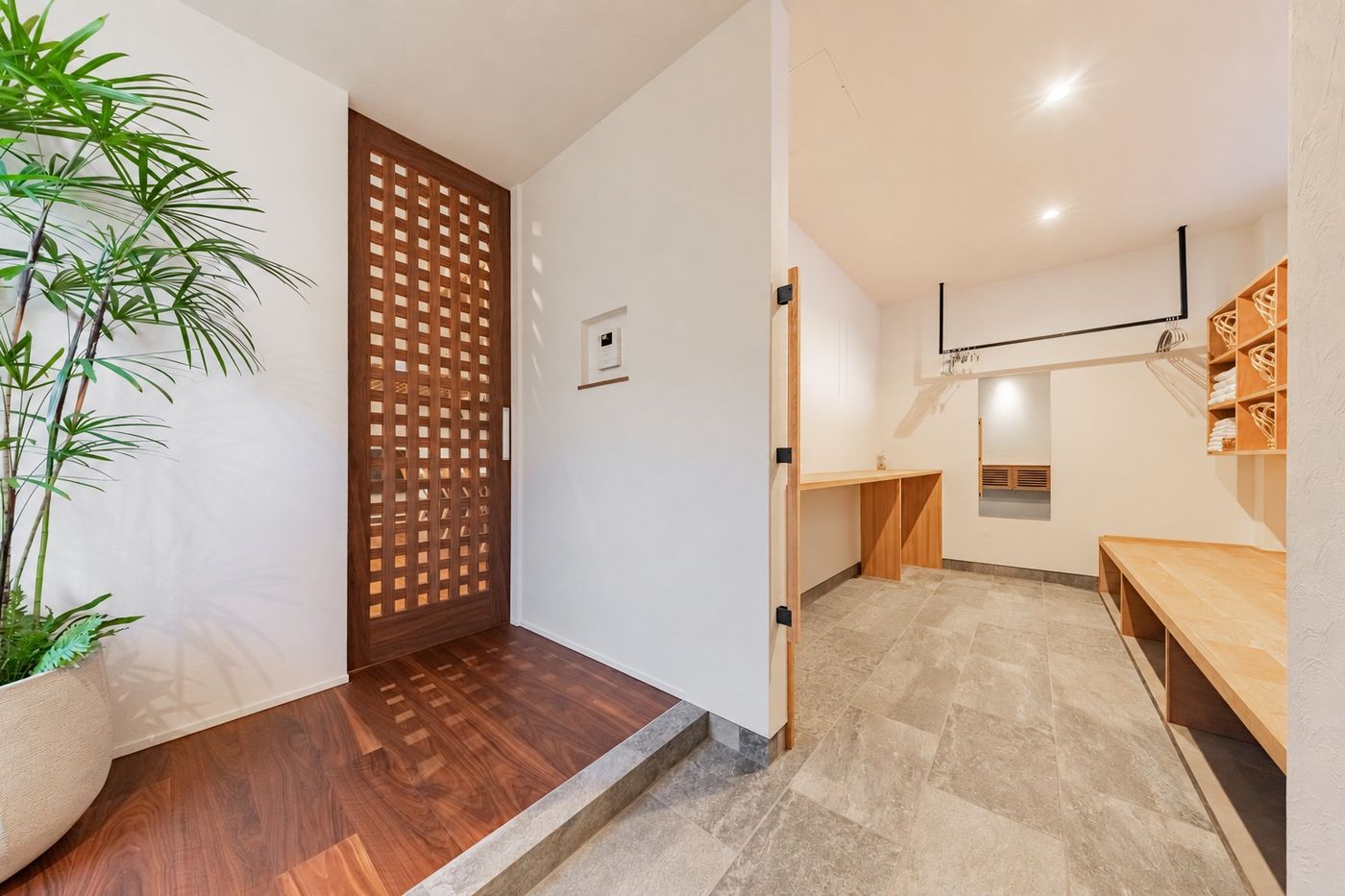 The entrance of Rin: a latticed wooden door, a potted plant, and the trunk room beyond