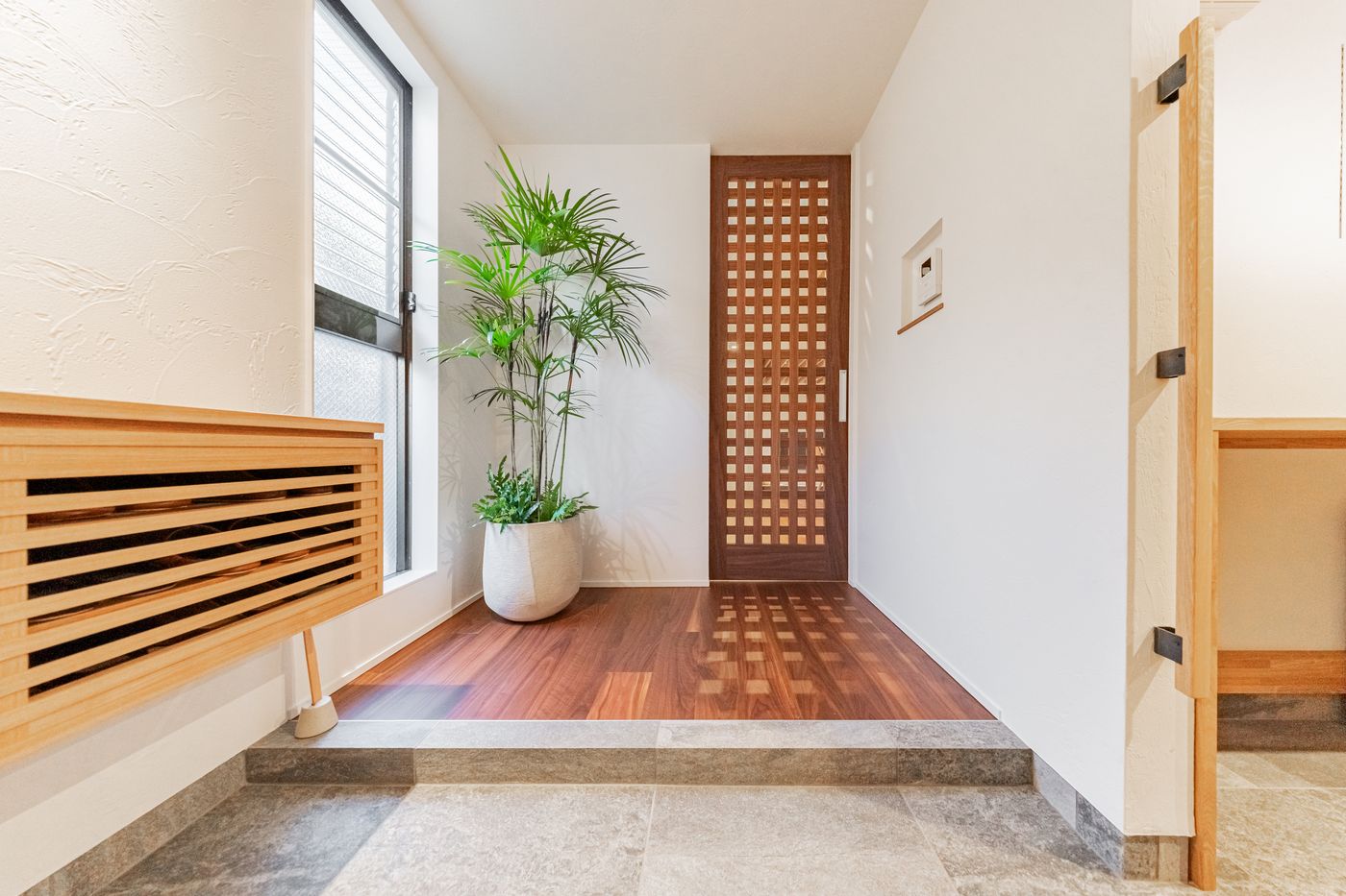 The entrance hall of Rin with a latticed wooden door and a potted plant