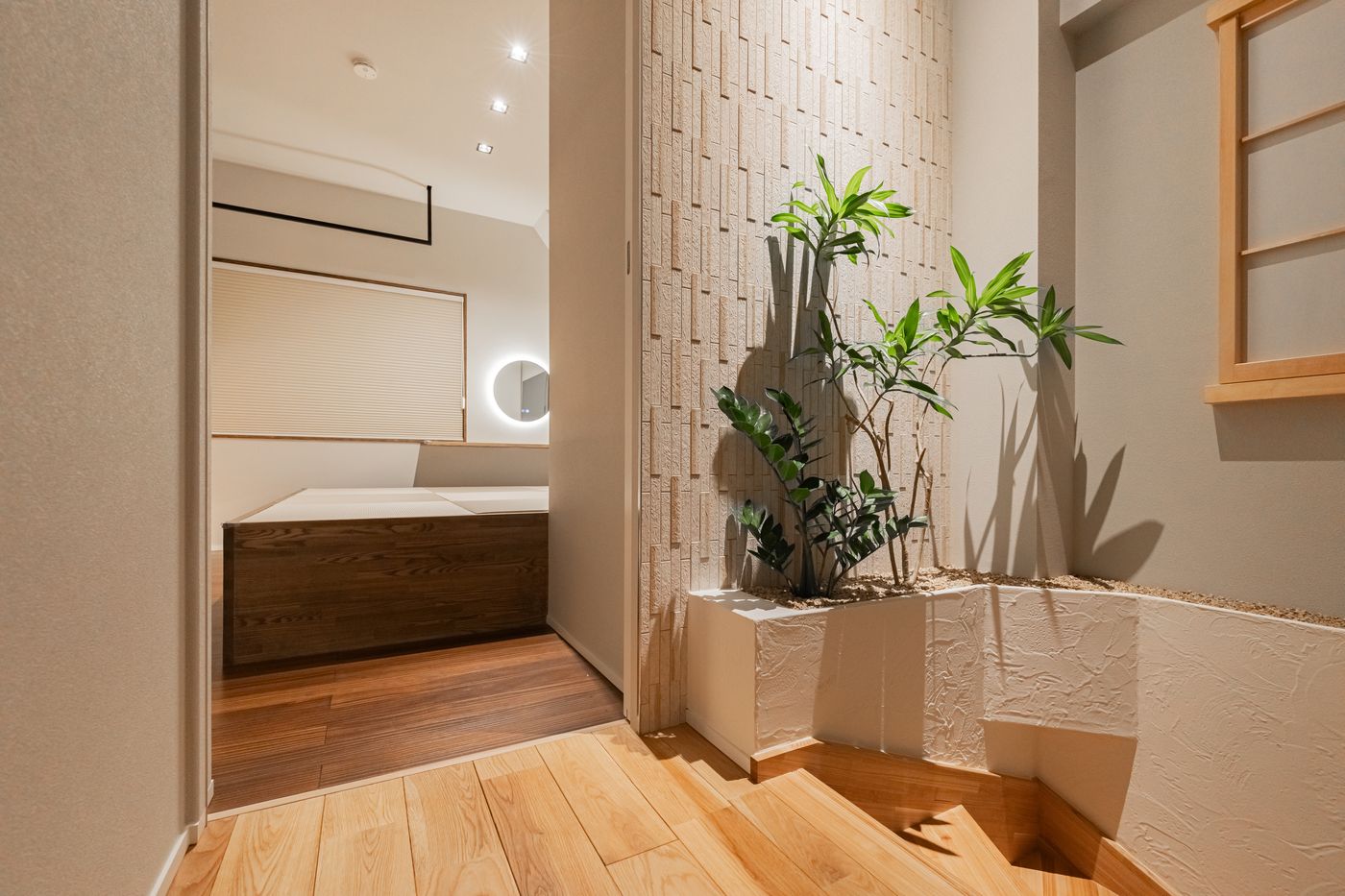 A hallway with a potted plant and a view into a bedroom