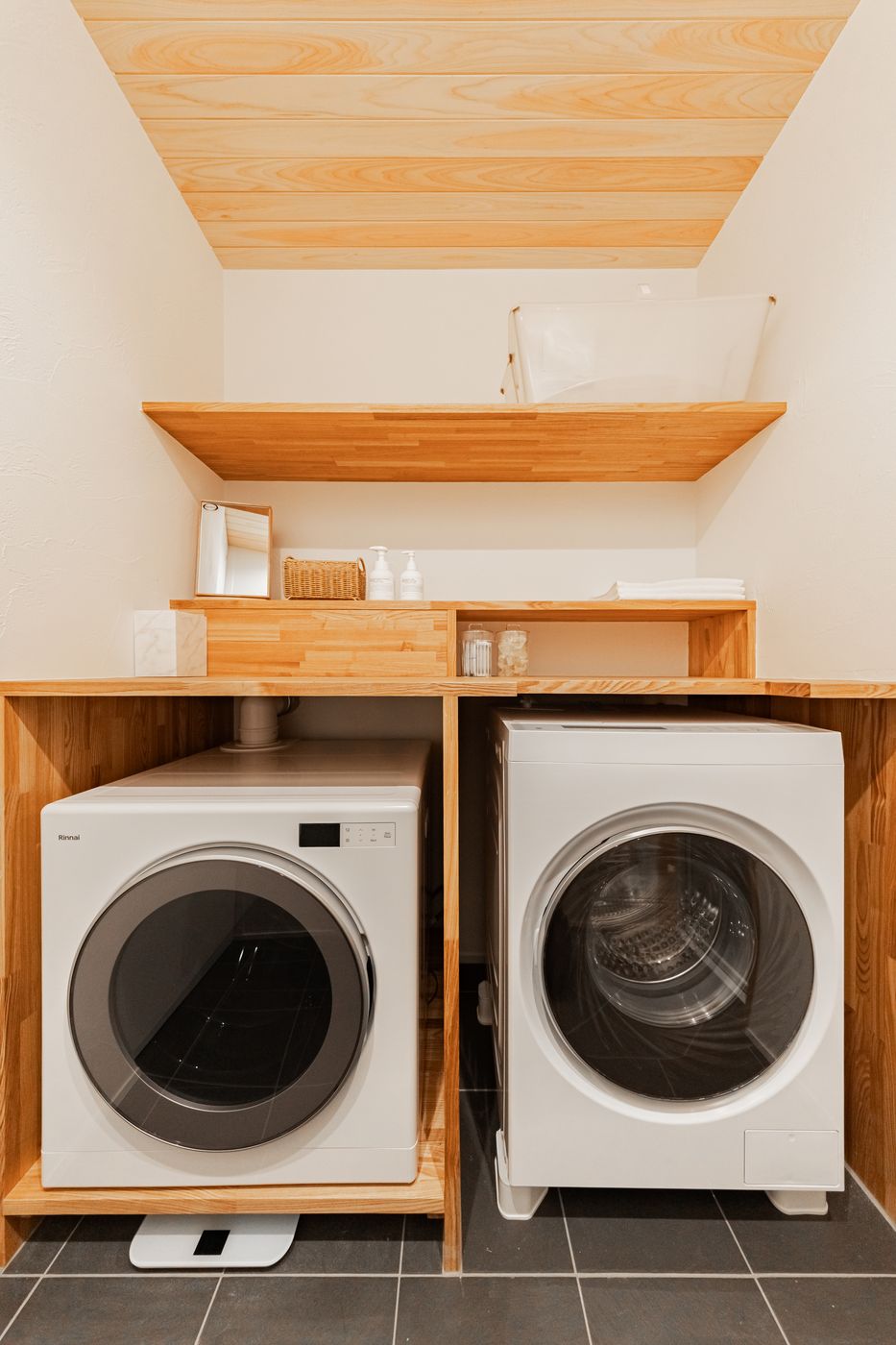 Two washer-dryers under a wooden counter