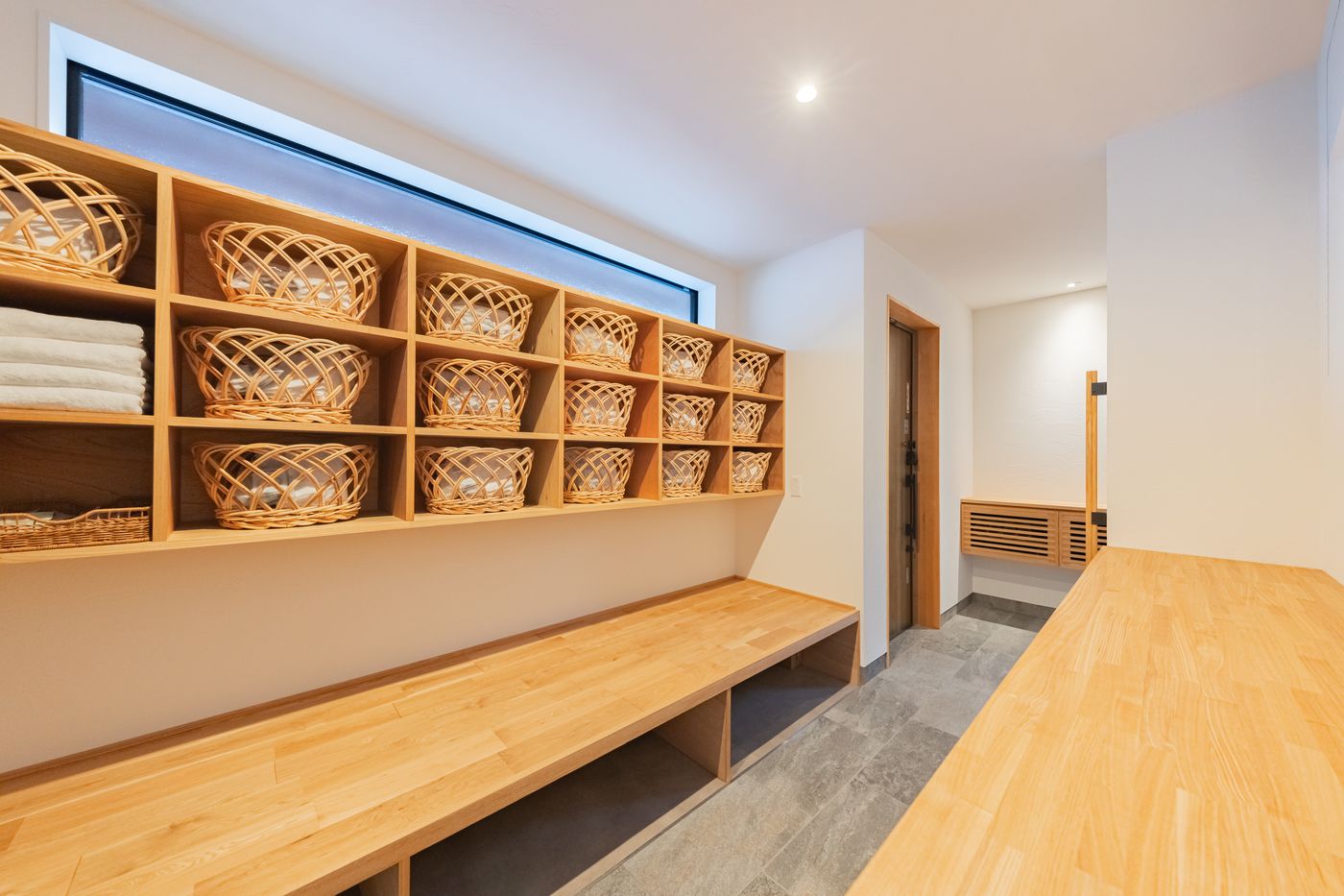 The trunk room: a wall of woven baskets above a long wooden bench